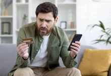 Nešťastný muž s kreditní kartou a mobilem