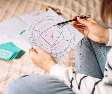 Mladá žena sedí na zemi a před sebou má horoskop, který zkoumá