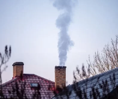 Čoudící komín rodinného domu a záběr na zasněžené střechy