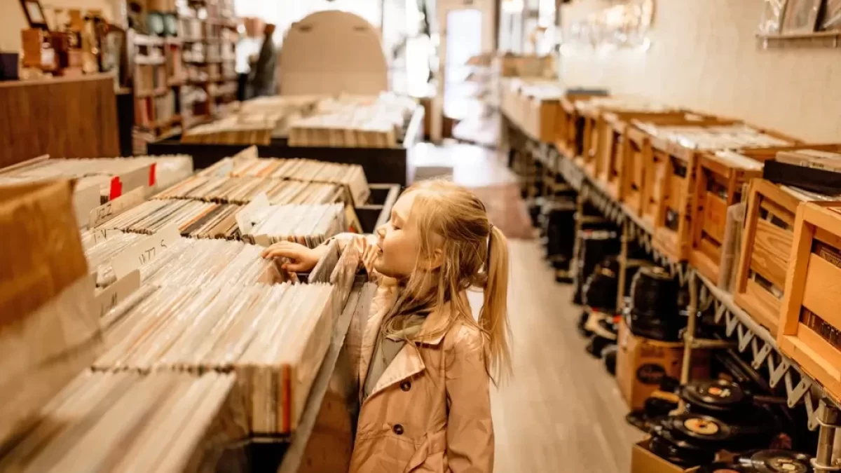 Malá holčička si prohlíží regály plné starých vinylových desek