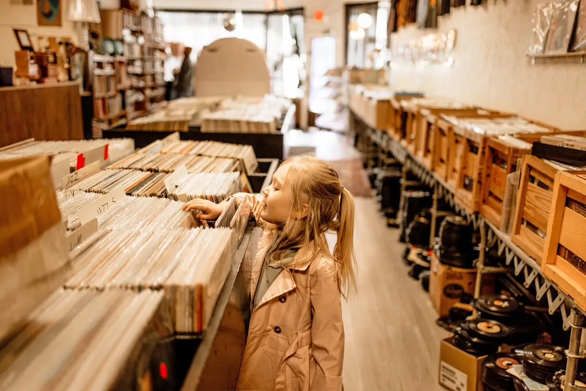 Malá holčička si prohlíží regály plné starých vinylových desek