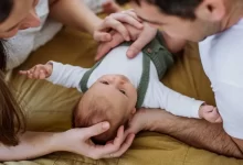 Rodiče leží na sedačce a sledují láskyplně své miminko, které je mezi nimi