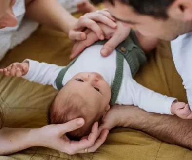 Rodiče leží na sedačce a sledují láskyplně své miminko, které je mezi nimi