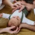 Rodiče leží na sedačce a sledují láskyplně své miminko, které je mezi nimi