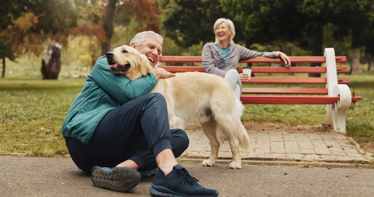 Pár seniorů si užívá na lavičce v parku svého čtyřnohého psího miláčka