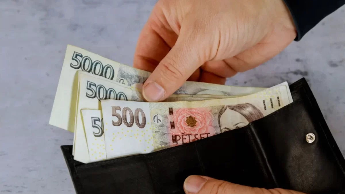 Ruka vyndává české bankovky z peněženky