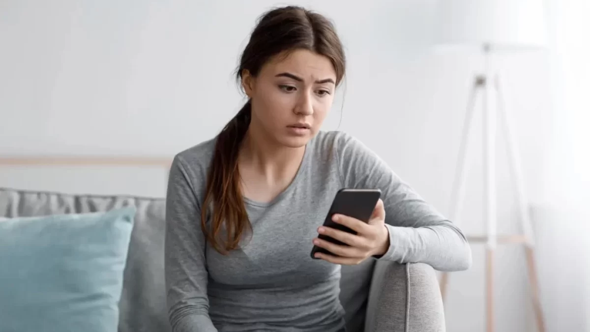 Žena sklesle kouká na mobil
