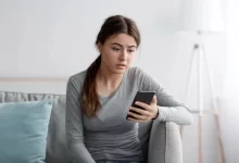 Žena sklesle kouká na mobil
