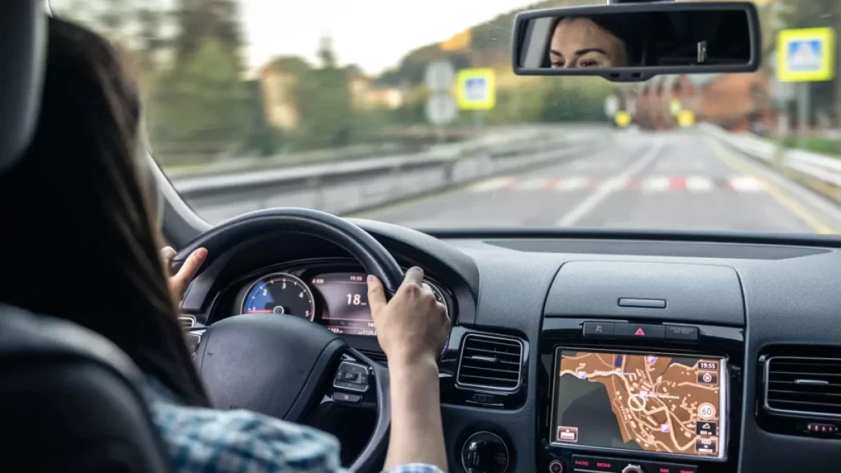Řidička sleduje silnici při jízdě autem, pohled z interiéru na čelní sklo a zpětné zrcátko.