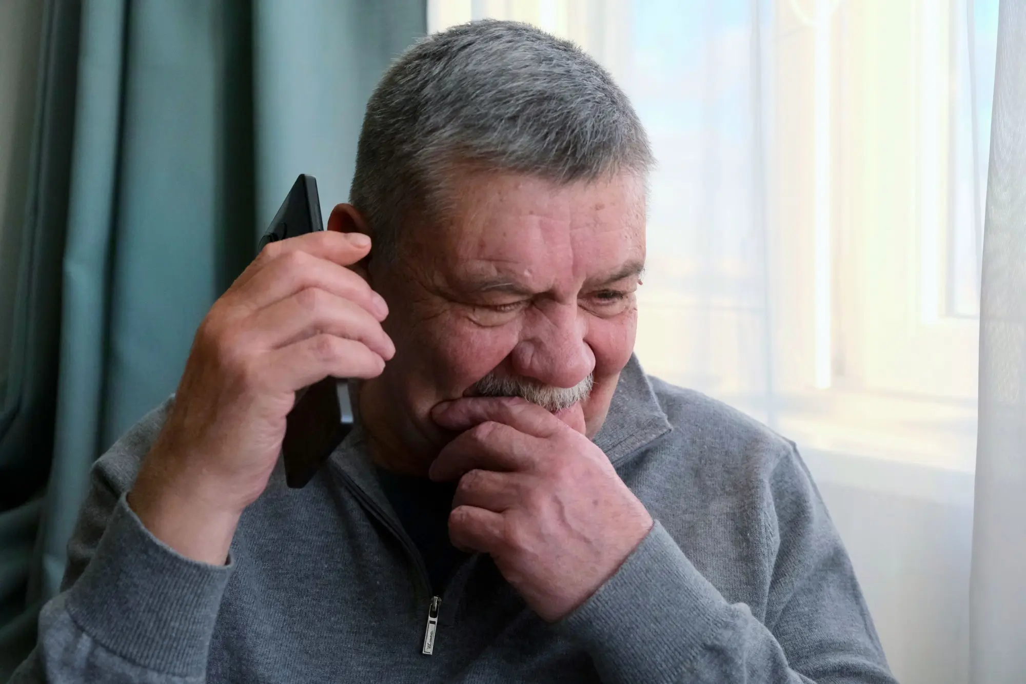 Zamyšlený starší muž při telefonování