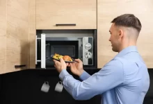 Muž si dává ohřát jídlo do mikrovlnné trouby