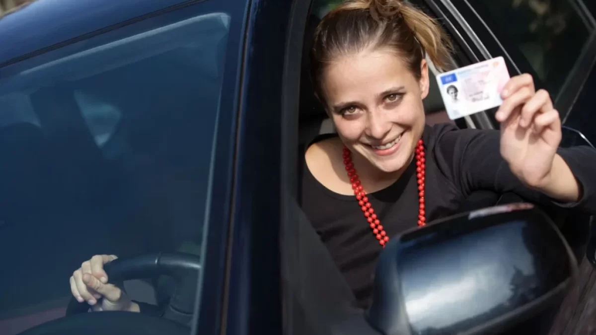 Žena za volantem ukazuje řidičský průkaz