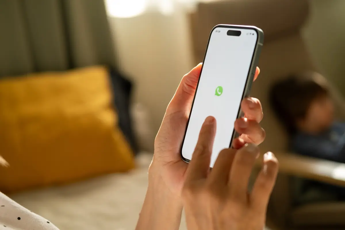 WhatsApp 1 - SportDeník Mladé ženské ruce s mobilním telefonem v ruce, na displeji ikona aplikace WhatsApp