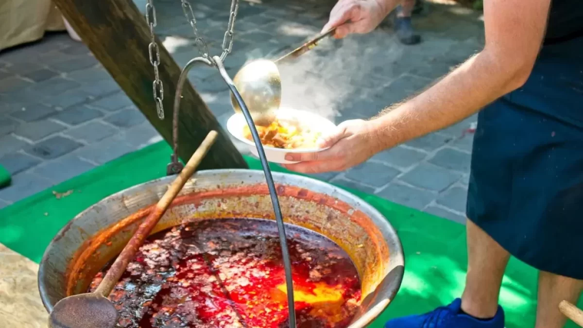 Muž v zástěře vaří kotlíkový guláš na ohni
