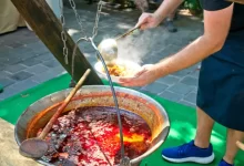 Muž v zástěře vaří kotlíkový guláš na ohni