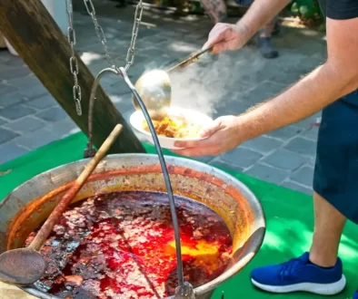 Muž v zástěře vaří kotlíkový guláš na ohni