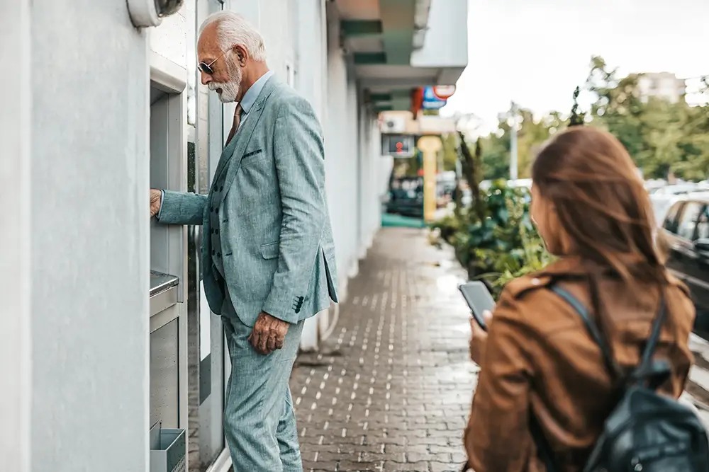 Podvodníci požádají o pomoc a okradou vás. - SportDeník studentka čeká, až pán vybere z bankomatu peníze