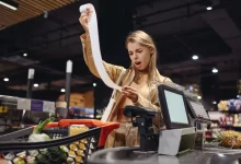 zděšená žena s účtenkou u pokladny v supermarketu