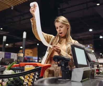 zděšená žena s účtenkou u pokladny v supermarketu