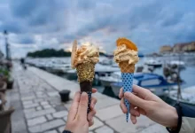 Promenáda u moře v Chorvatsku a před ní ve vzduchu dvě ruce s kornoutem zmrzliny
