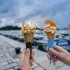Promenáda u moře v Chorvatsku a před ní ve vzduchu dvě ruce s kornoutem zmrzliny