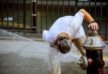 Mladý muž se chladí vodou v městské fontánce