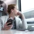 Žena s mobile v ruce a nasazenými sluchátky sedící ve vlaku