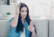 Zděšená žena koukající do mobilu