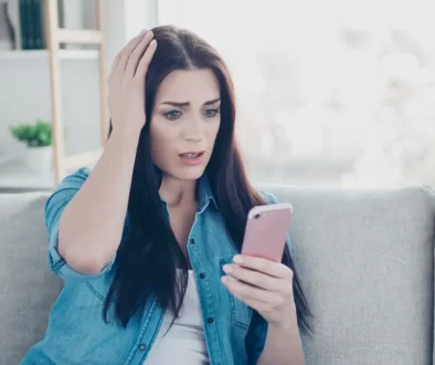 Zděšená žena koukající do mobilu