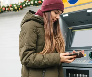 Dívka používající mobil u bankomatu