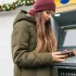 Dívka používající mobil u bankomatu