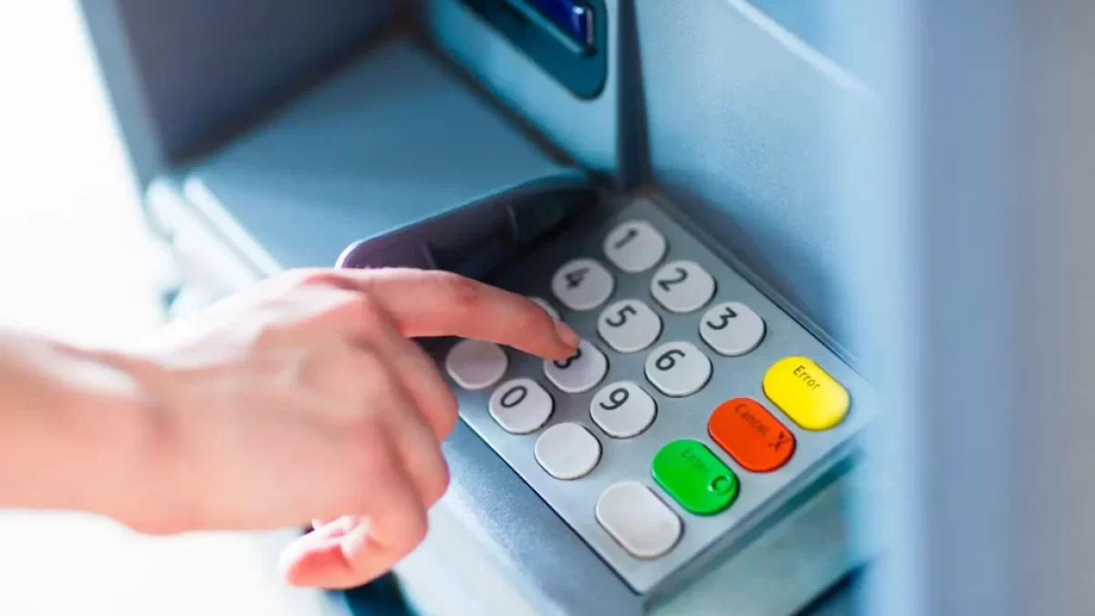 Detail ruky při ovládání tlačítek bankomatu.