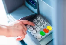 Detail ruky při ovládání tlačítek bankomatu.