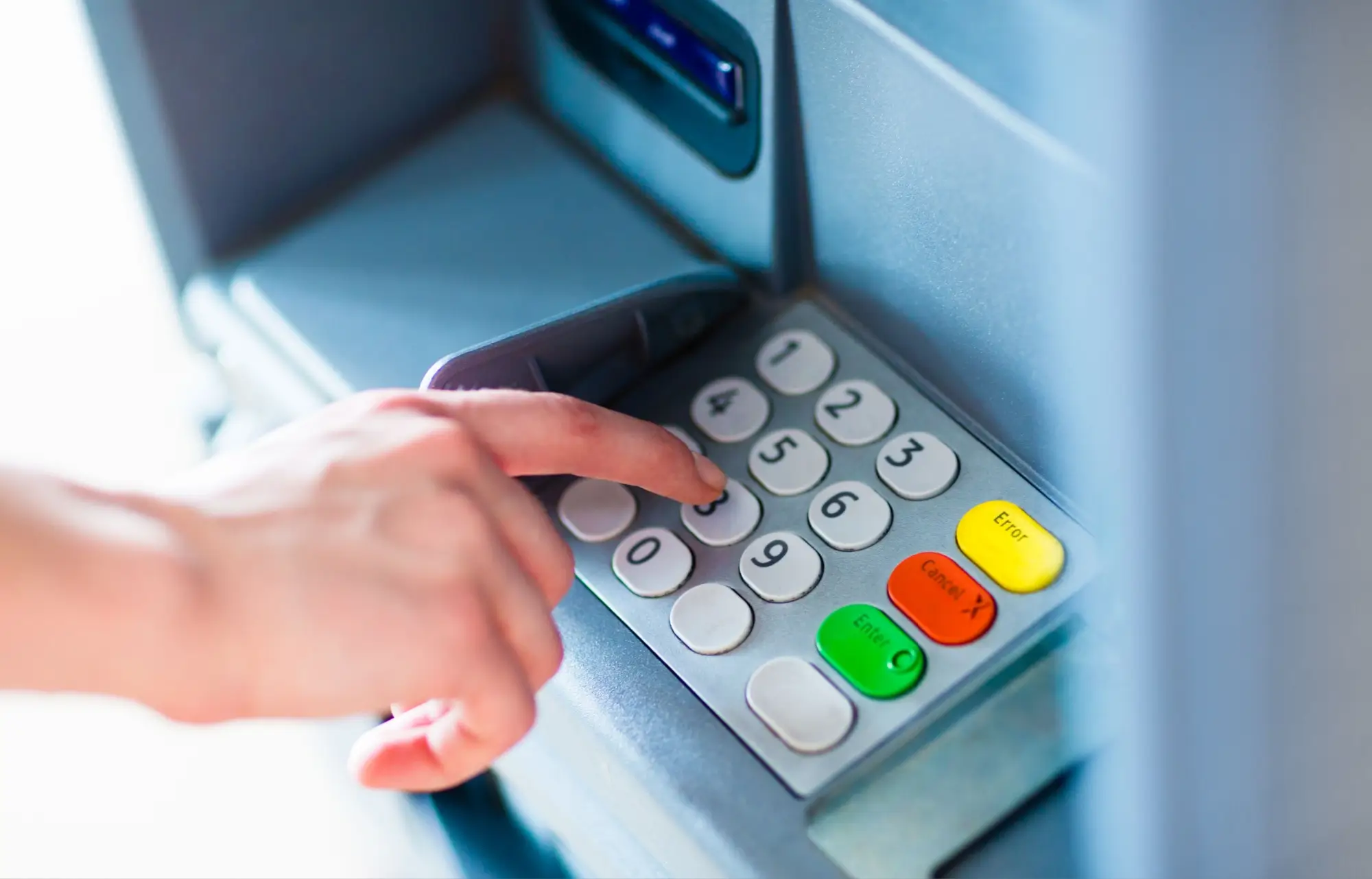 Detail ruky při ovládání tlačítek bankomatu.