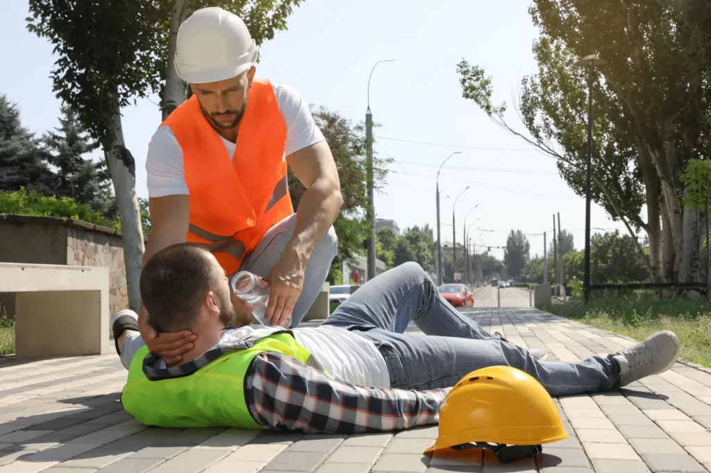Shutterstock_2019923978 - SportDeník Dělník podávající vodu kolegovi ležícímu na zemi