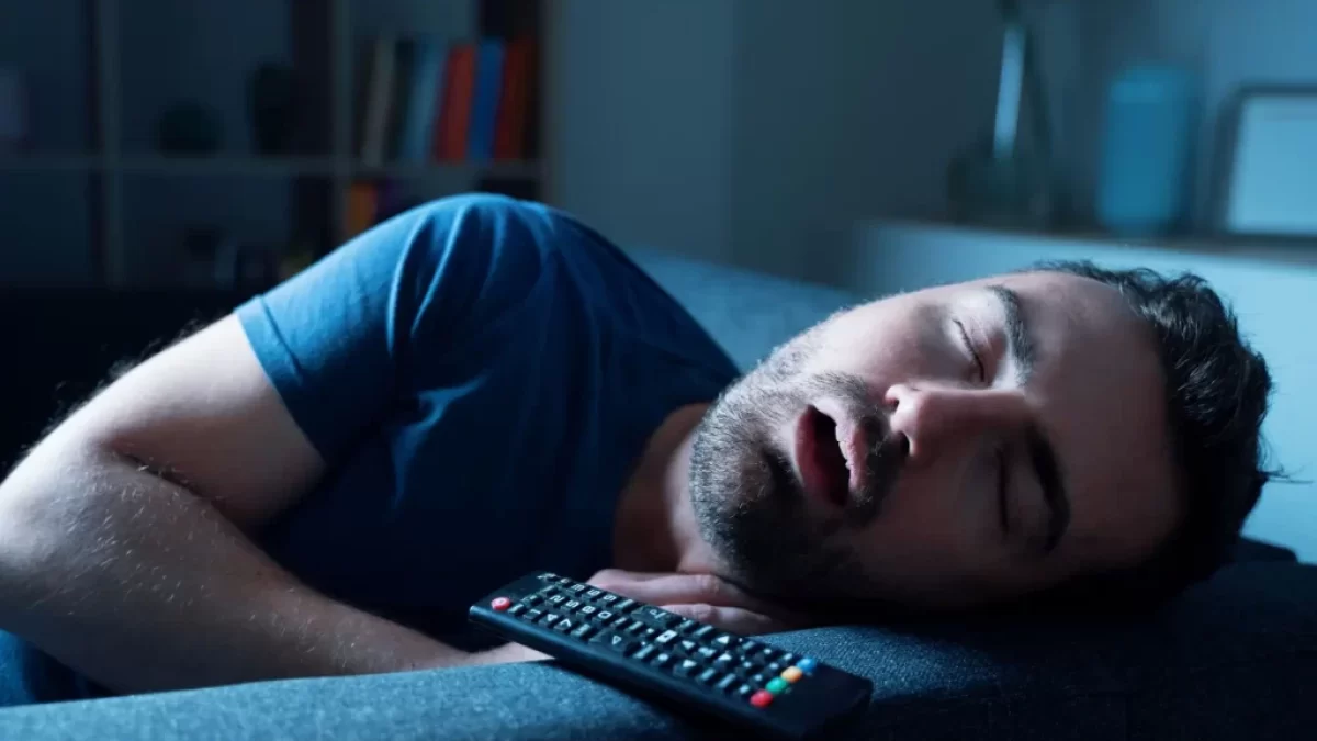 Muž spící při zapnuté televizi.
