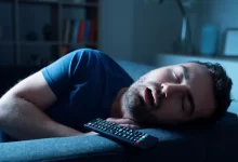 Muž spící při zapnuté televizi.