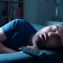 Muž spící při zapnuté televizi.