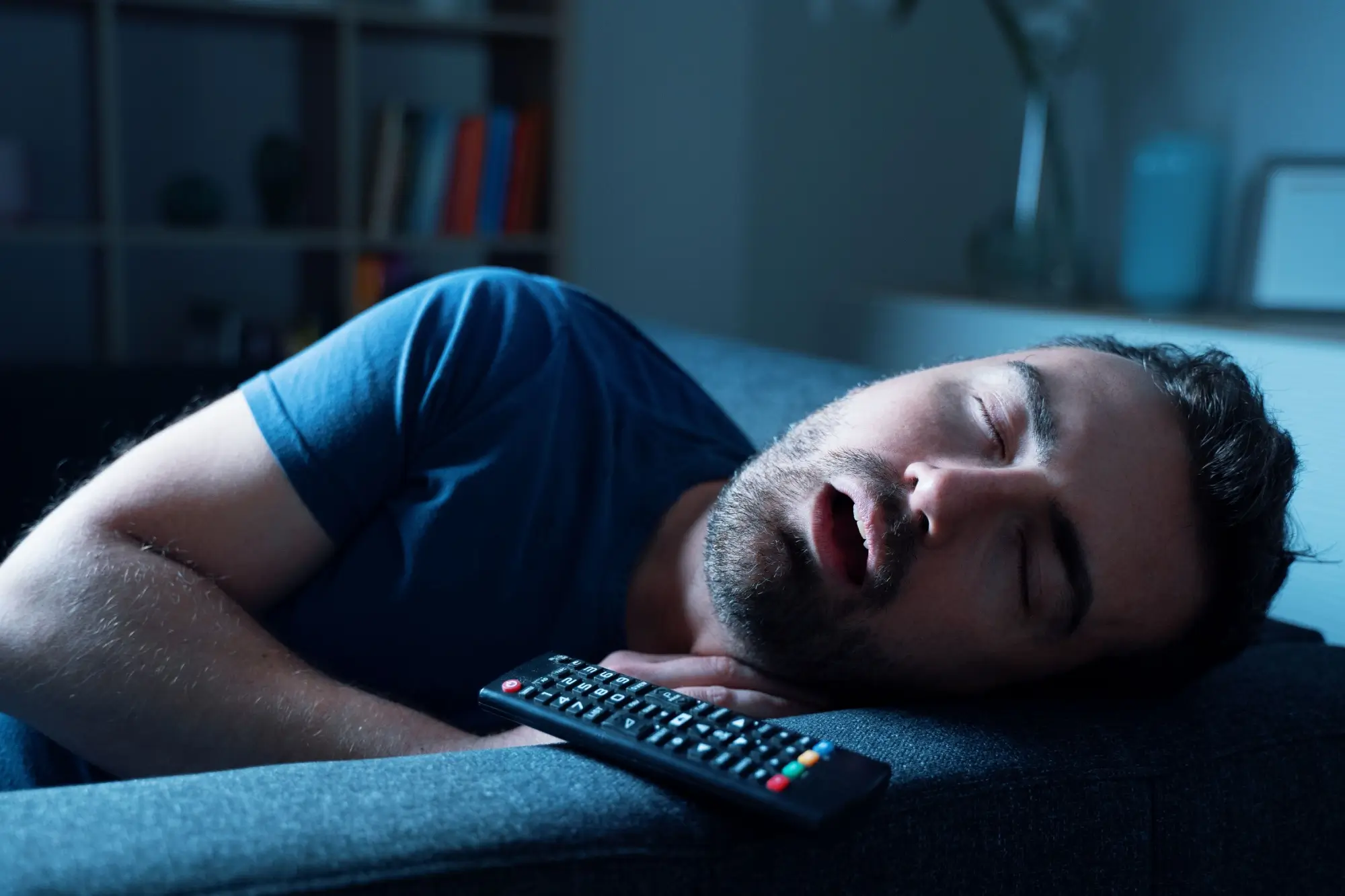 Muž spící při zapnuté televizi.