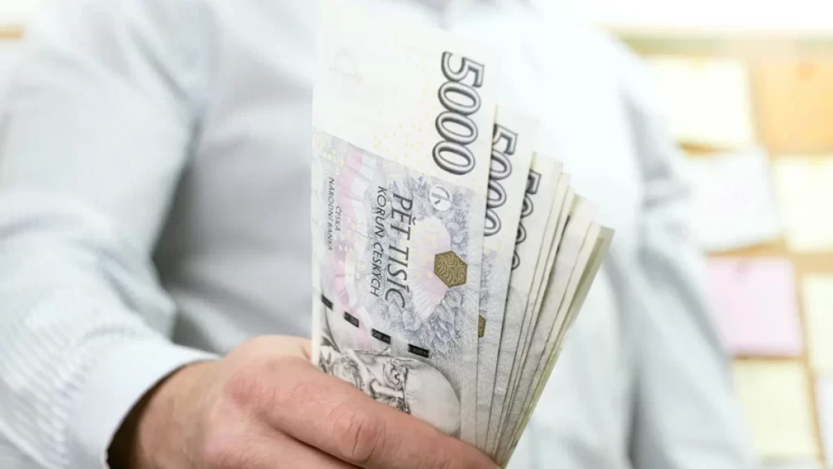 Muž držící bankovky o hodnotě 5 000 Kč