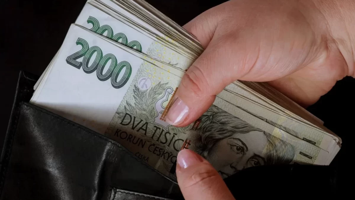 Ruka vyndávající dvoutisícové bankovky z peněženky