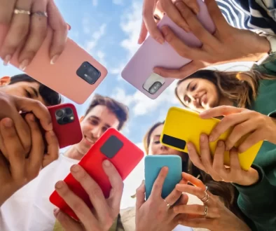 Skupina mladých lidí drží mobilní telefony různých barev.