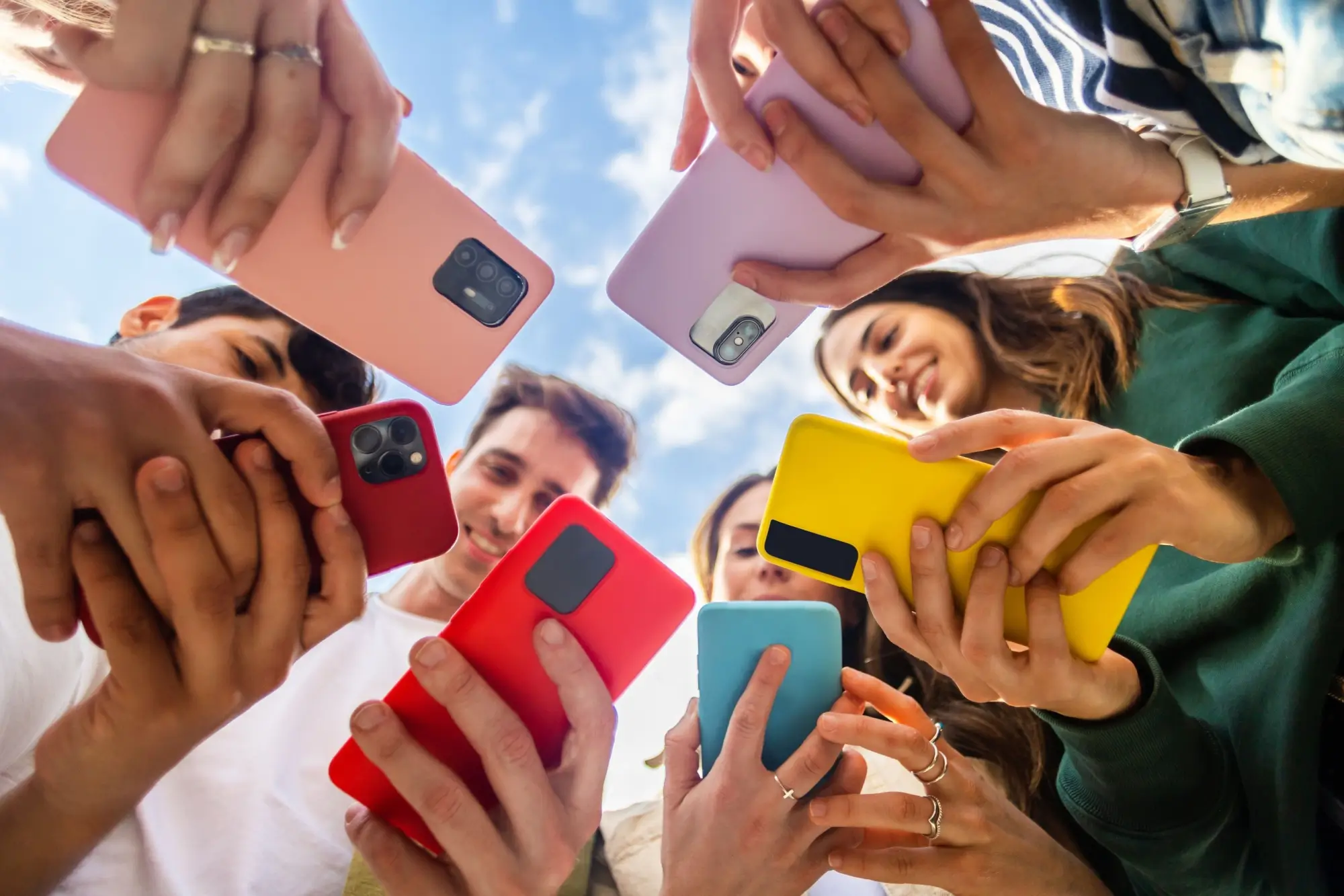 Skupina mladých lidí drží mobilní telefony různých barev.