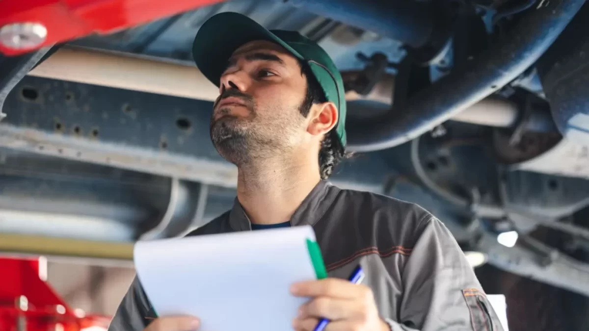 Technik při kontrole spodní části vozidla během STK