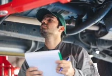 Technik při kontrole spodní části vozidla během STK