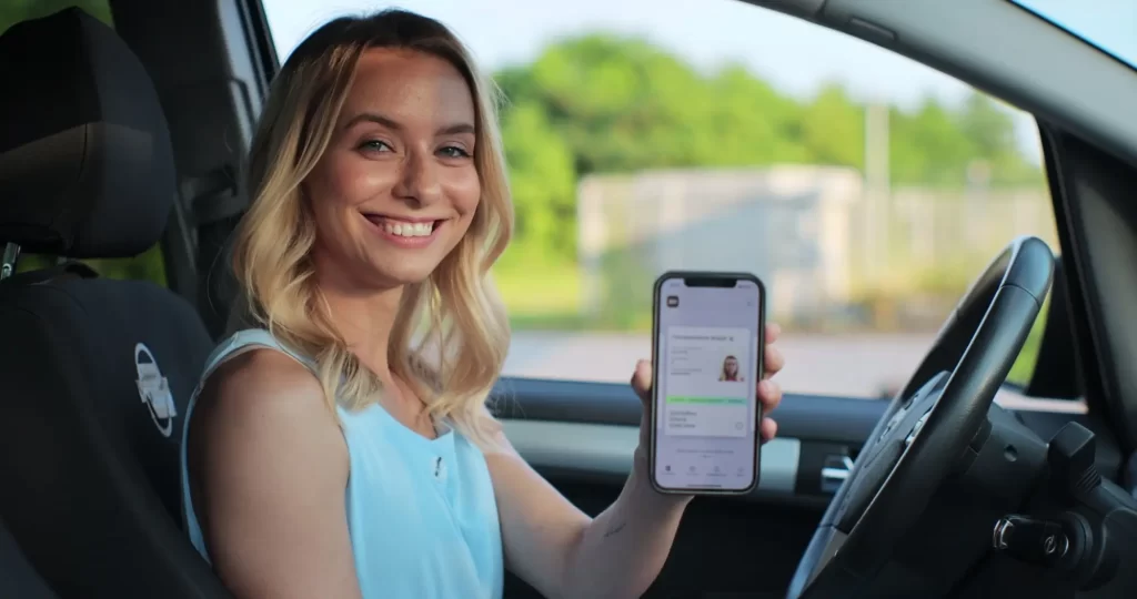 - SportDeník Žena ukazující digitální řidičský průkaz v mobilní aplikaci.