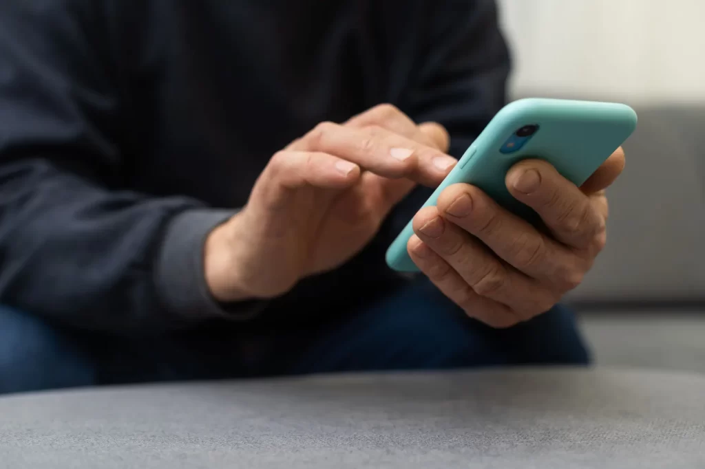 Shutterstock_2372082703 - SportDeník Mužské ruce držící smartphone