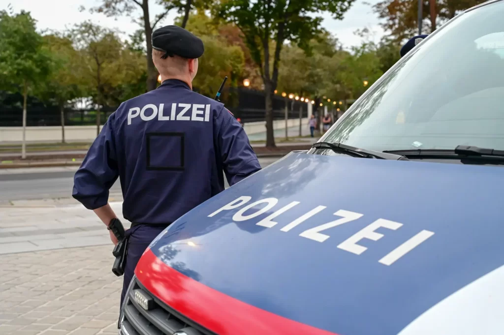 Shutterstock_2377602467 - SportDeník Příslušník rakouské policie stojící u policejního vozu