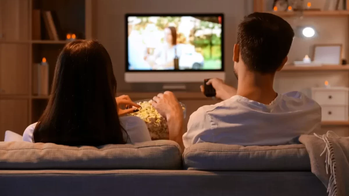 Mladý pár s popcornem sledující televizi