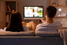 Mladý pár s popcornem sledující televizi